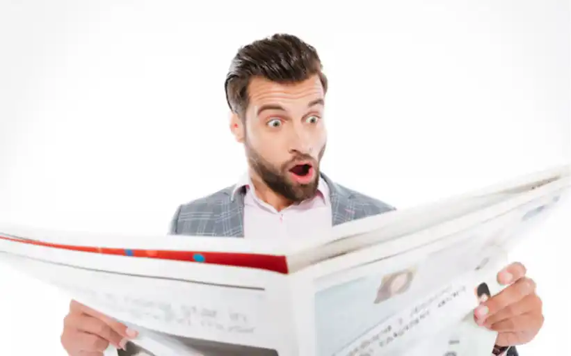Latest Ridiculosity! a young man dressed in a grey suit reading the newspaper, he appears to be in shock.